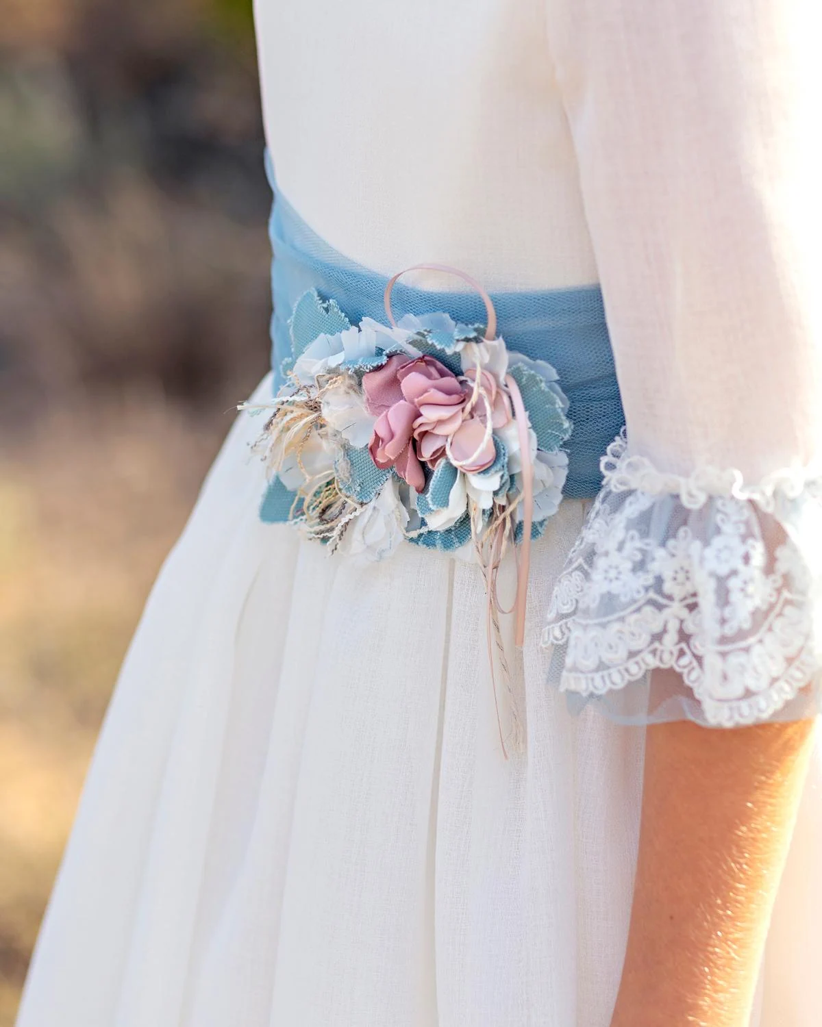 Detalle del fajín del Carmy 5804: tul azul, ramillete de flores rosa y azul y manga con volante de encaje