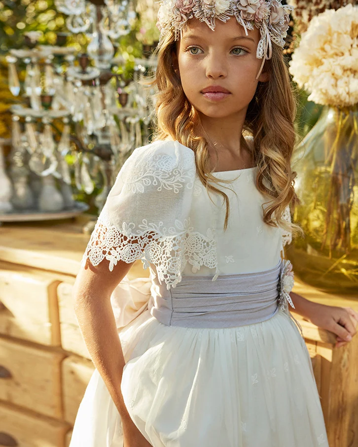 Vestido de comunión Rosa Clará First R701 de cerca: manga de encaje calado y fajín plisado gris lavanda